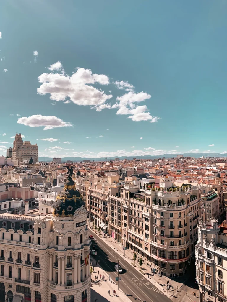 An elevated view of the historic Metropolis Building dome overlooking the streets and rooftops of Madrid