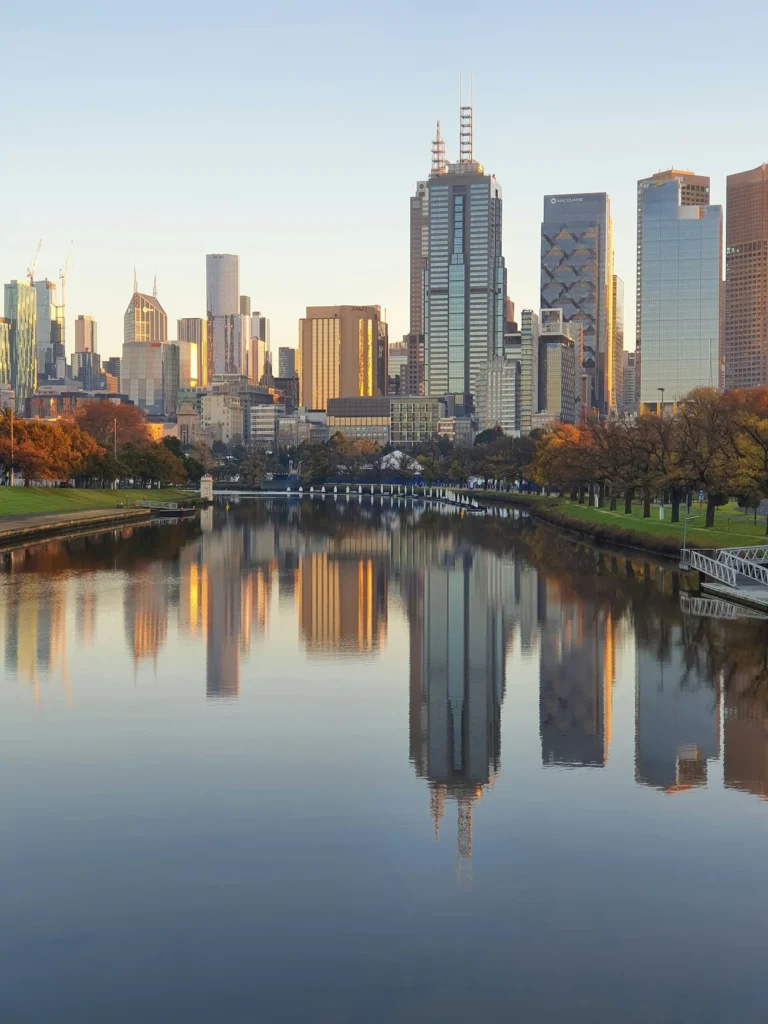 Melbourne skyline skyscrapers reflecting perfectly on the calm surface of the Yarra River during golden hour