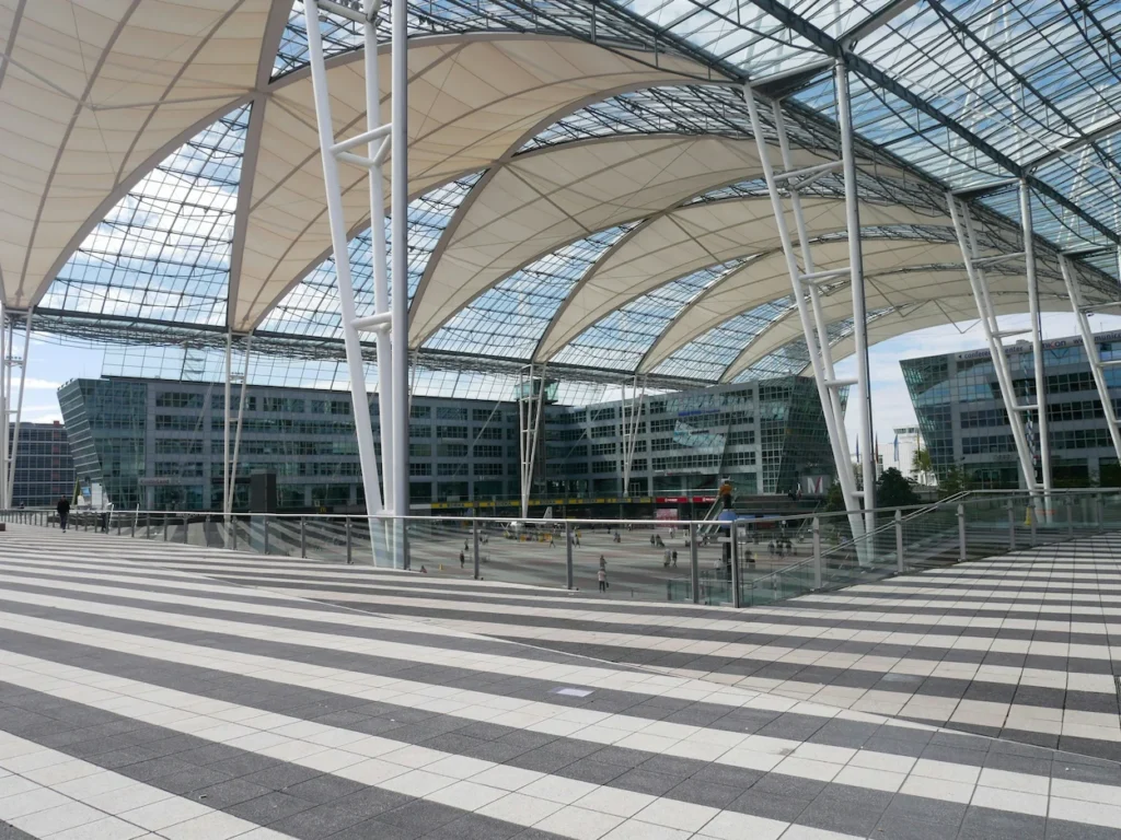Striped plaza tiles under the large arched glass roof of the Munich Airport Center