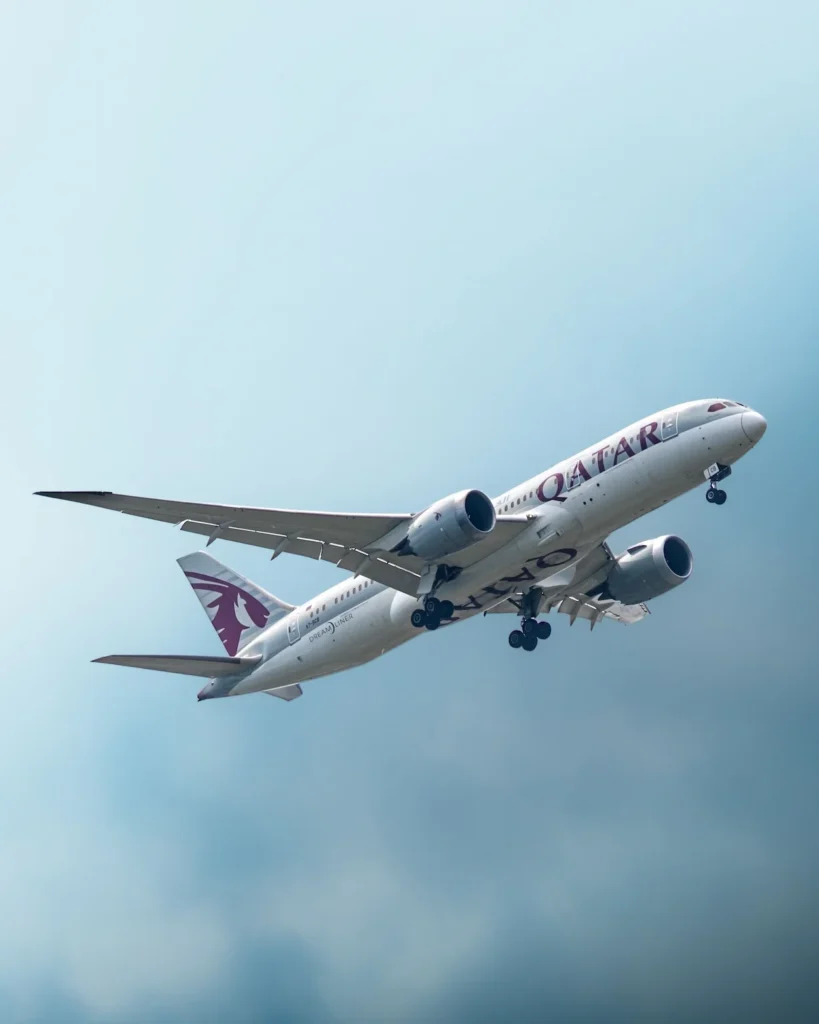 Qatar Airways Boeing 787 Dreamliner commercial passenger plane climbing through a bright sky after takeoff
