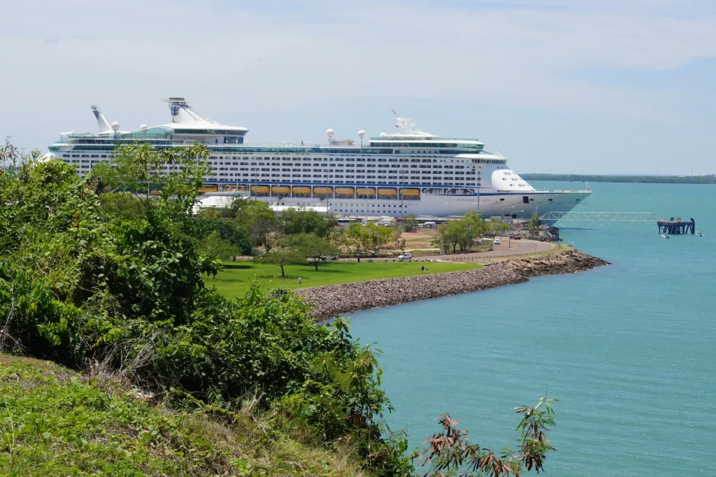 Royal Caribbean Voyager of the Seas cruise ship docked at a port terminal behind a green park