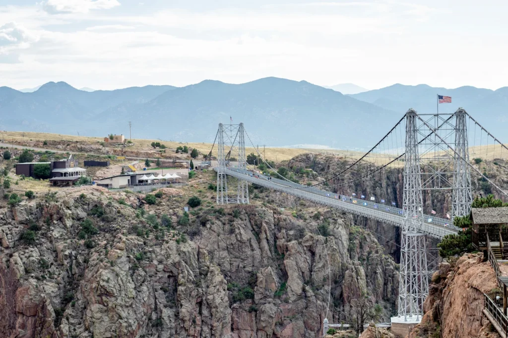 Suspension bridge spanning a deep rocky canyon with mountains in the background at Royal Gorge Bridge and Park