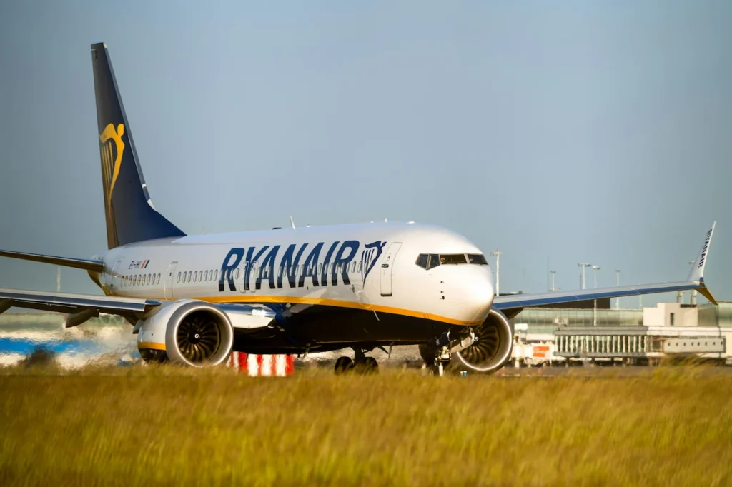 A Ryanair Boeing 737 taxiing on an airport runway with golden grass in the foreground