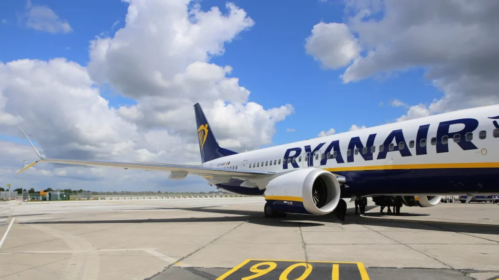 A side view of a blue and white Ryanair Boeing 737 airplane parked on an airport tarmac