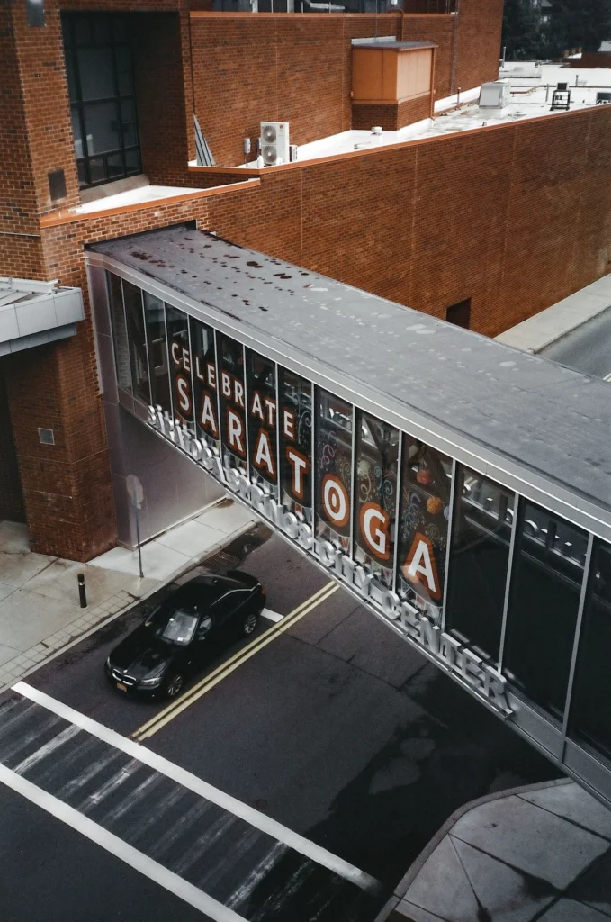 Saratoga Springs City Center enclosed pedestrian skybridge crossing over a street with a black car