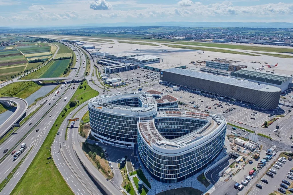 Aerial view of the figure-eight SkyLoop building next to the highway and runway at Stuttgart Airport