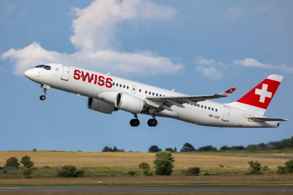 A Swiss International Air Lines Airbus A220 airplane ascending into a blue sky