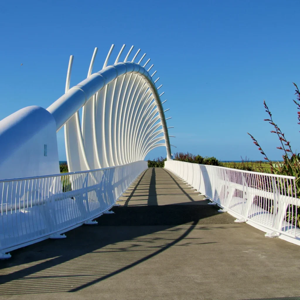 A white rib arched pedestrian bridge on the New Plymouth coastal walkway under a clear blue sky