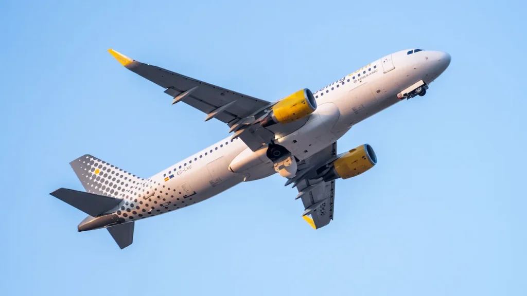 Vueling Airbus A320 commercial jet climbing steeply into a clear blue sky after takeoff