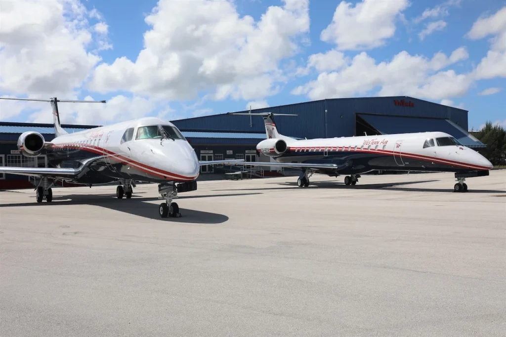 Two Western Air Embraer ERJ-145 regional passenger jets parked outside a hangar on the tarmac