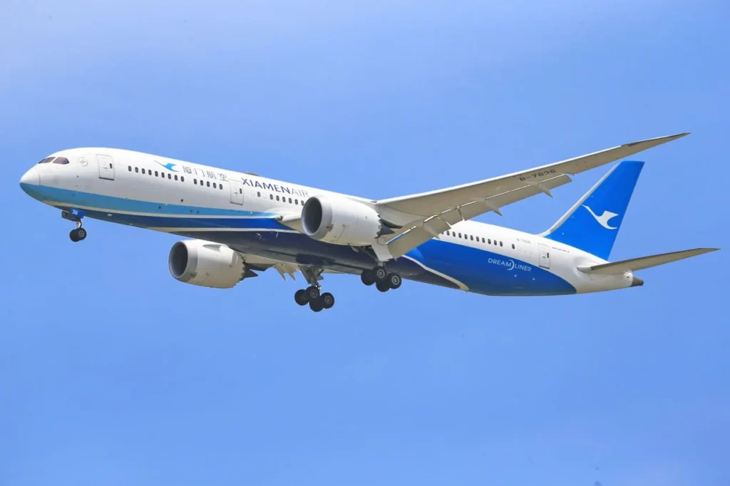 Xiamen Airlines Boeing 787-8 Dreamliner passenger airplane soaring through a clear blue sky
