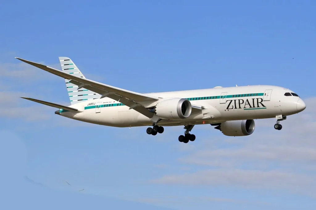 Zipair Tokyo Boeing 787 passenger airplane descending through a clear blue sky with landing gear deployed