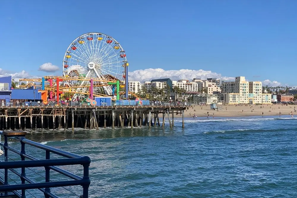 The Santa Monica Pier with its colorful Ferris wheel and amusement rides by the ocean.