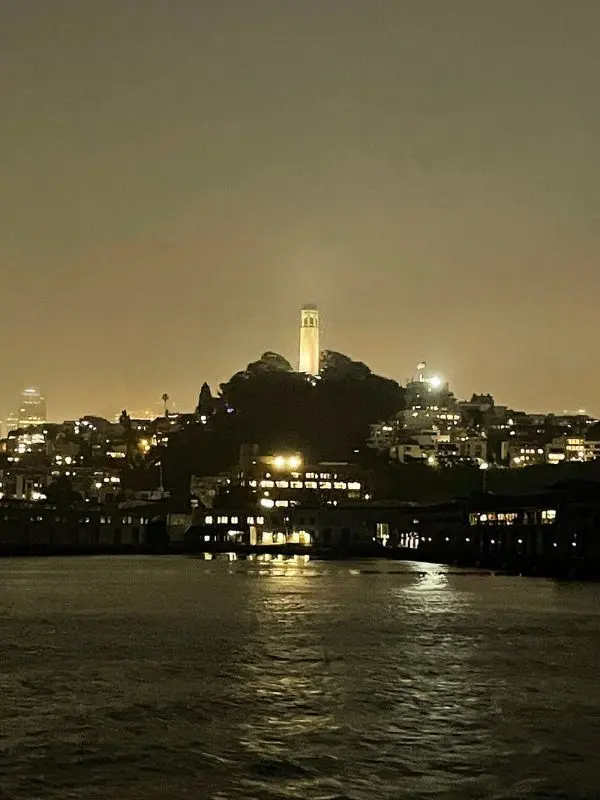 Coit Tower glowing on a hill during Alcatraz night tours.
