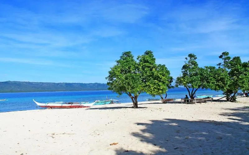 Small boats rest on the sandy shore of Alibijaban Island.
