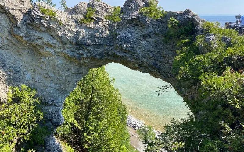 A natural limestone arch frames the shoreline view at Arch Rock on Mackinac Island.