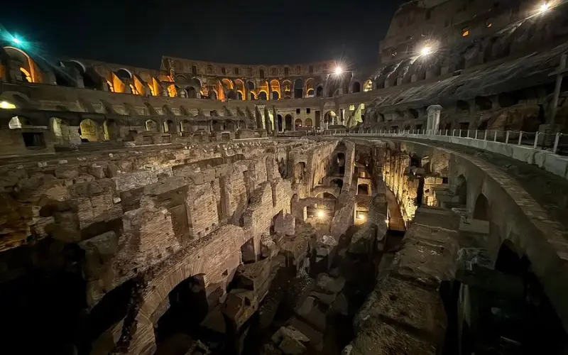 Colosseum in Rome, Italy lit up at night with ancient ruins.