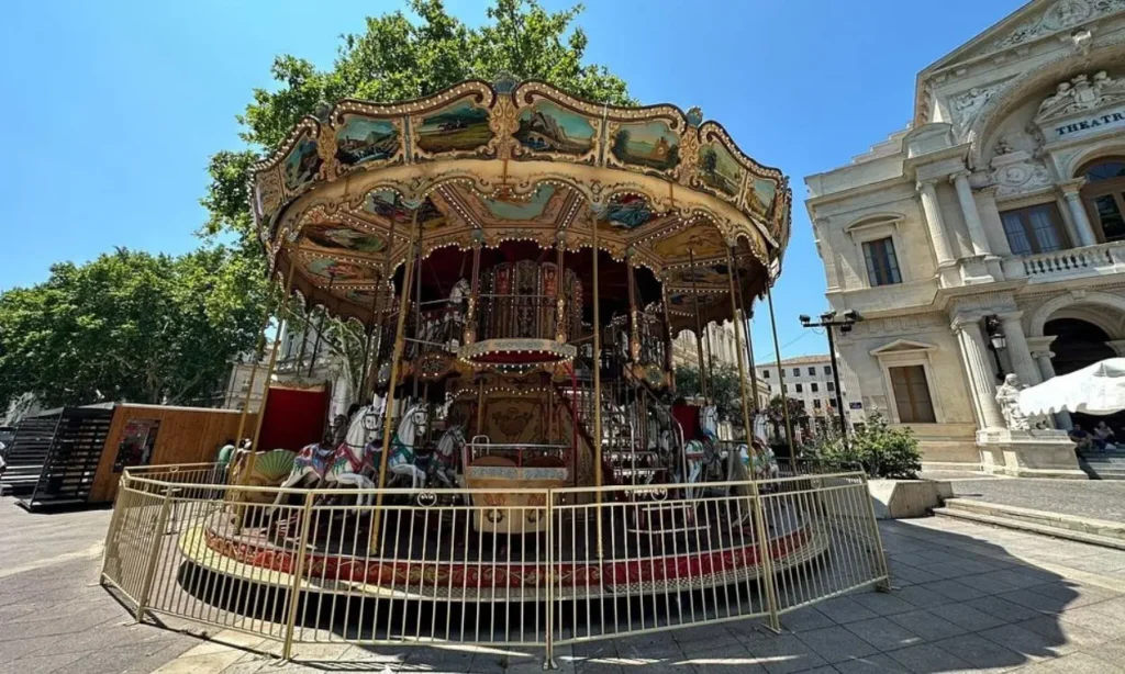The colorful carousel at Place de l'Horloge in front of a historic building.