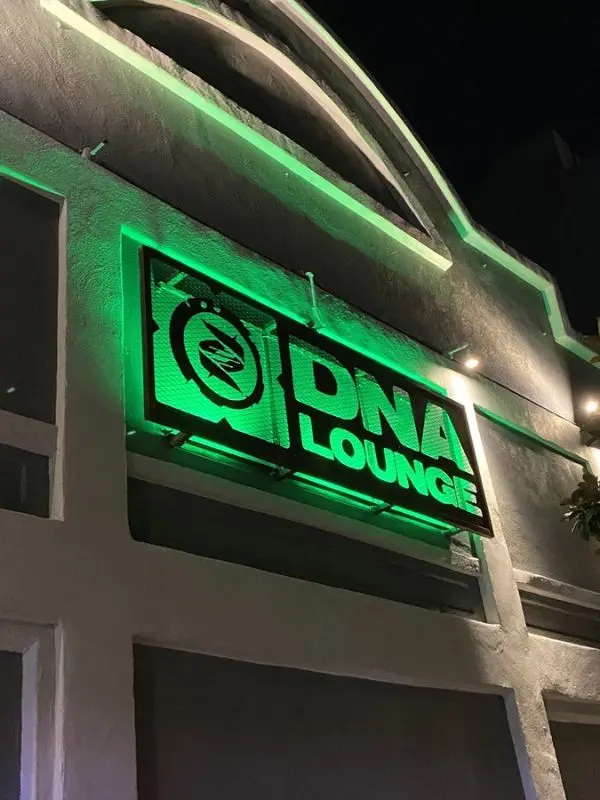 Neon green sign of DNA Lounge on a dark night.