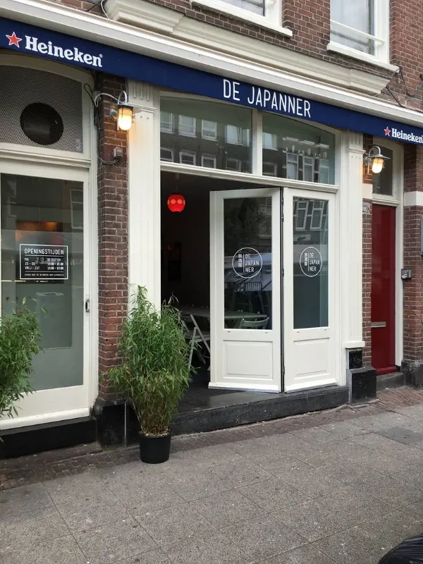 Entrance of De Japanner restaurant with open doors and bamboo plant.