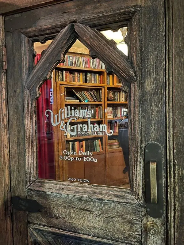 A wooden door with glass reveals bookshelves inside Williams & Graham speakeasy.