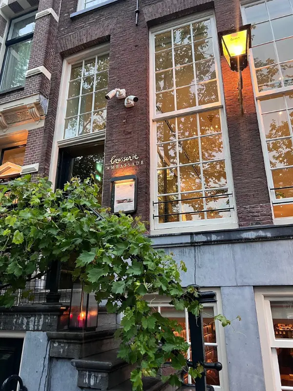 Elegant exterior of Brasserie Ambassade with tall windows and warm lighting.