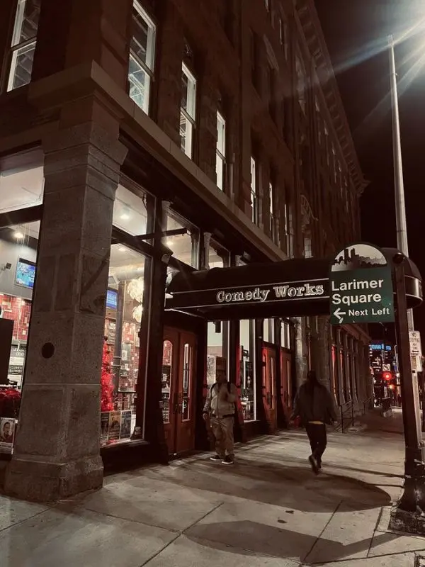 The Comedy Works entrance at night is lit with a sign pointing to Larimer Square.
