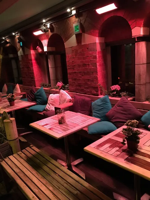 Cozy seating area with red lighting and cushions at Pasta e Basta.