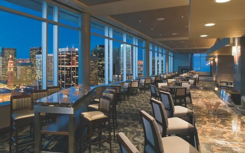 Large windows at Peaks Lounge showcase Denver’s skyline at night.
