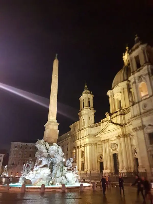 Piazza Navona in Rome, Italy with illuminated fountain and church at night.