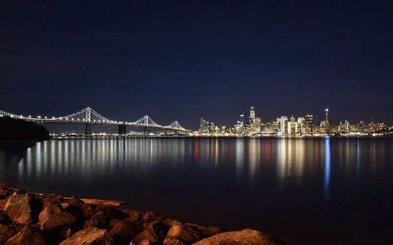 Bay Bridge and city lights reflecting on water from Treasure Island.