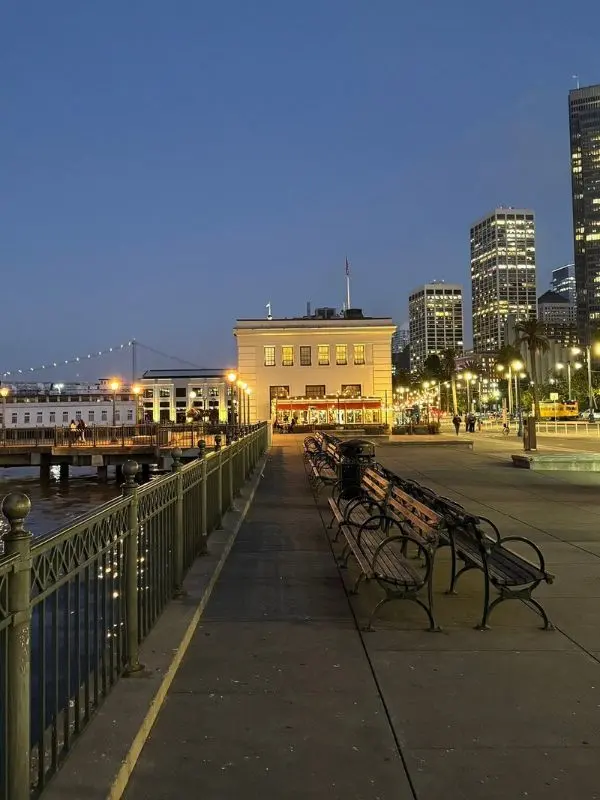 Evening view of the Embarcadero waterfront with benches and lights.