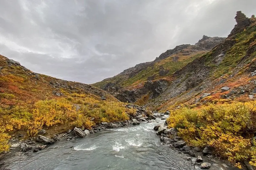A river running between rocky hills with autumn colors on the Savage River Loop Trail.