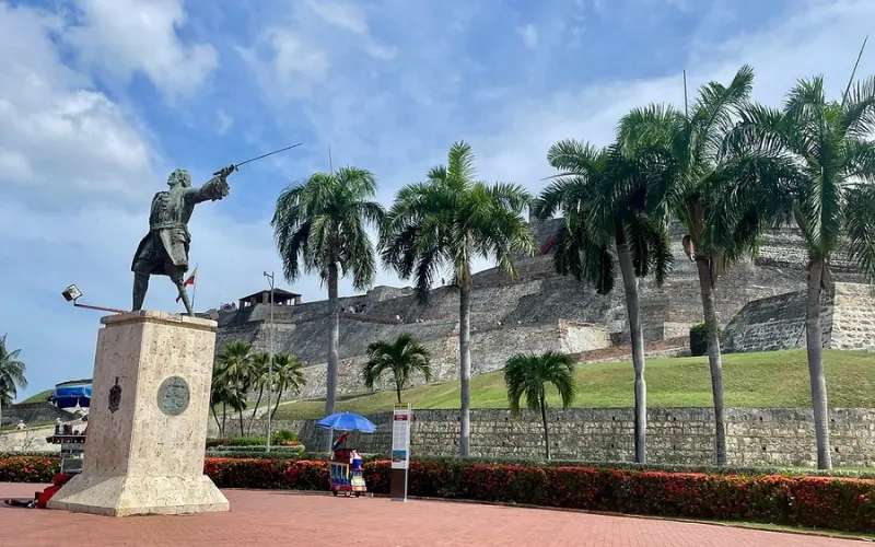 Statue and palm trees in front of Castillo San Felipe de Barajas fortress.