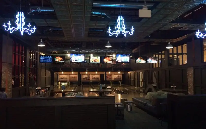 Neon chandeliers hang above bowling lanes inside Punch Bowl Social.