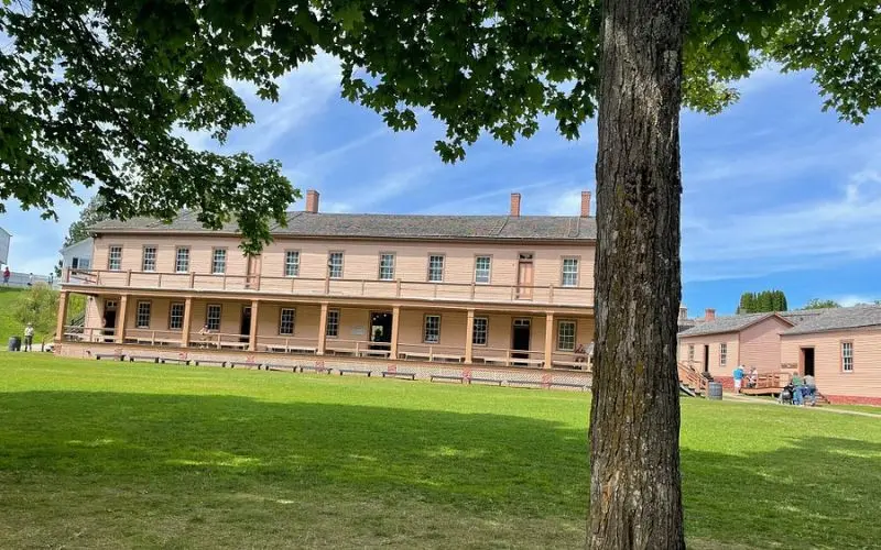 A long historic building stands on the grounds of Fort Mackinac.