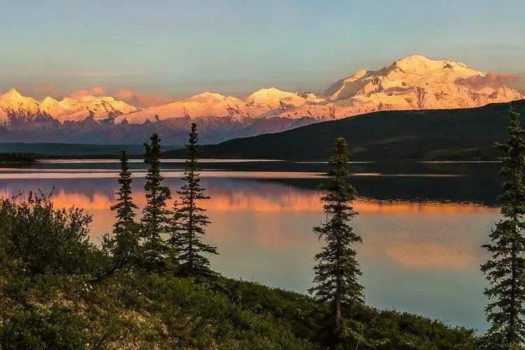 Snowy Mount Denali reflecting in Wonder Lake at sunset.