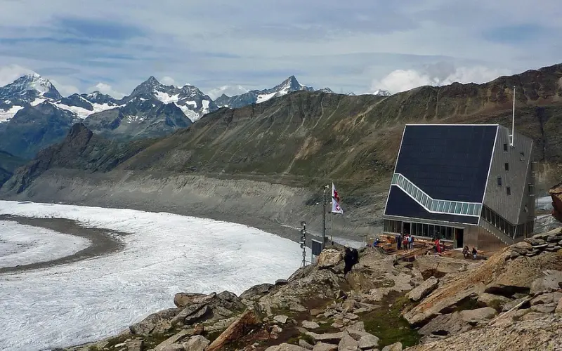 Monte Rosa Hut is a modern alpine hut perched near a glacier and surrounded by rugged peaks.
