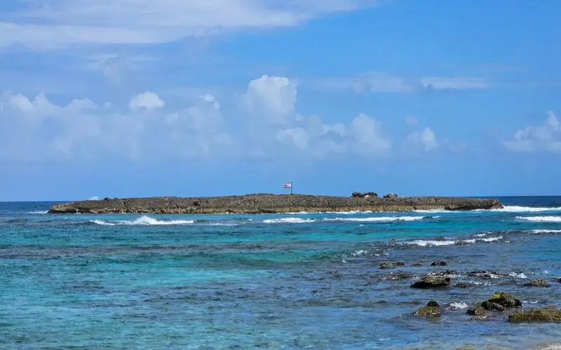 Small rocky island with a flag at Escambrón Marine Park.