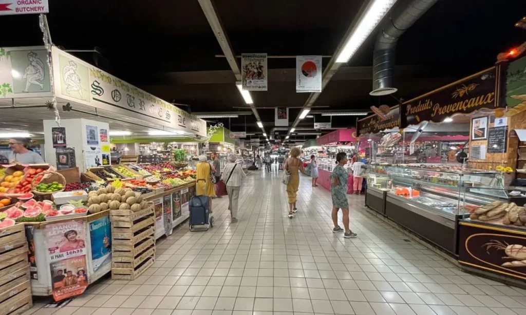 Stalls selling fruits, vegetables, and local products inside Les Halles Market in Avignon.