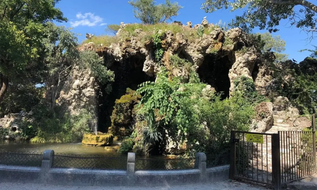 The rocky grotto and pond at Parc des Rochers des Doms surrounded by greenery.