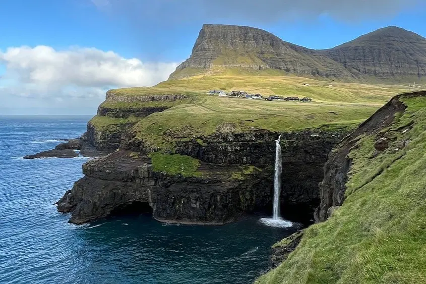 The Mulafossur Waterfall flowing into the ocean in the Faroe Islands.