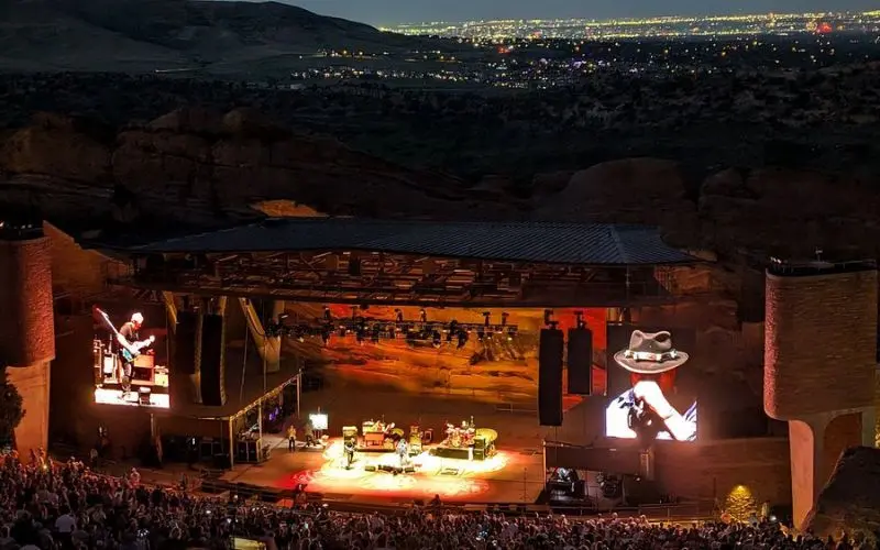 A concert takes place on stage at Red Rocks Amphitheatre at night.