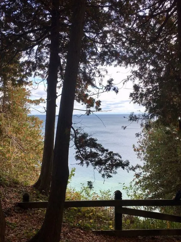 Trees frame a view of Lake Huron from Tranquil Bluff Trail on Mackinac Island.