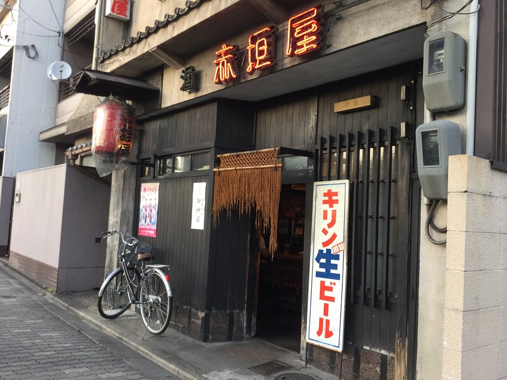 Exterior of Akagakiya with dark wooden facade, red lantern, and a bicycle parked outside.