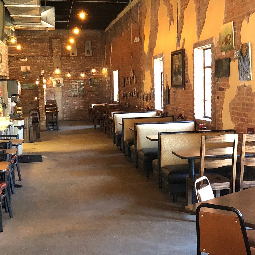 Rustic dining booths inside Alpha Omega with exposed brick walls.