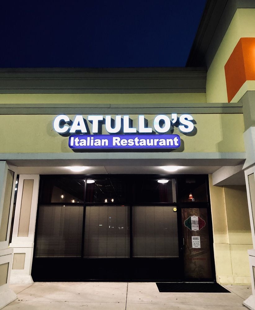 Exterior of Catullo's Italian Restaurant with a lit sign above the entrance.