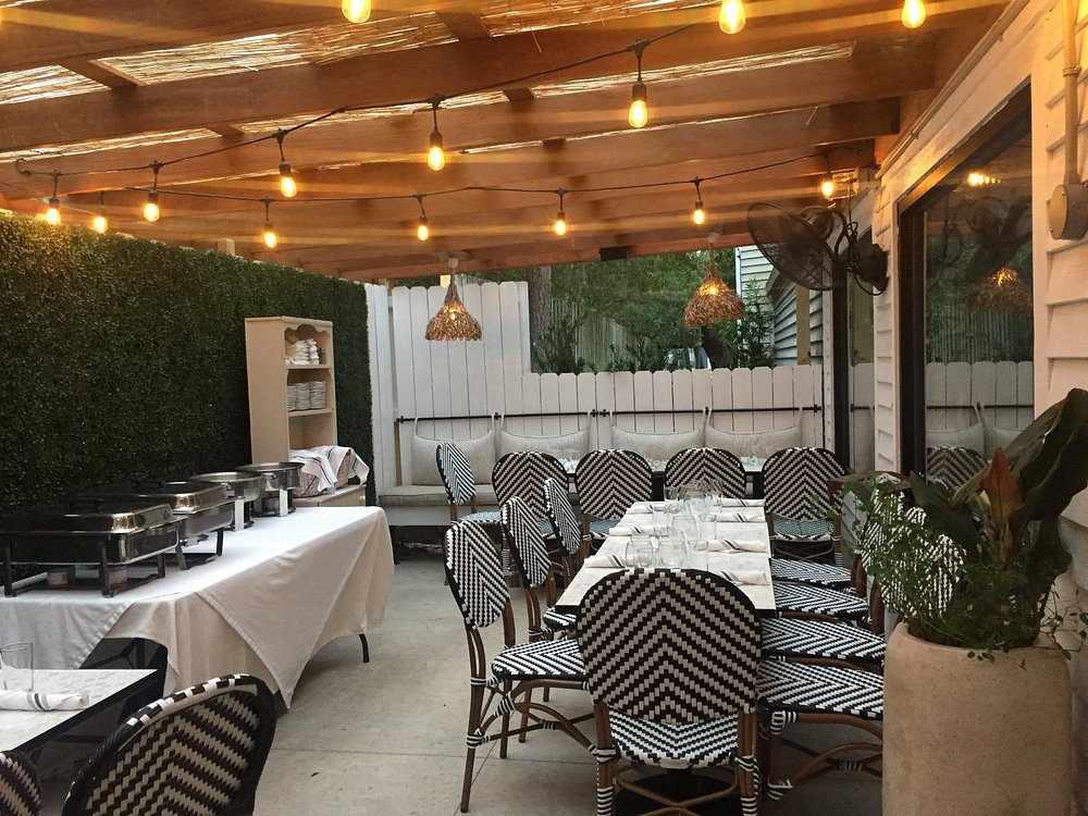 Outdoor patio at Ceviche's with string lights, wicker chairs, and set tables under a wooden pergola.