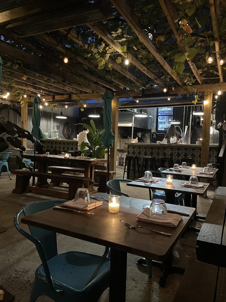 Outdoor dining area at Claro with string lights and open kitchen.