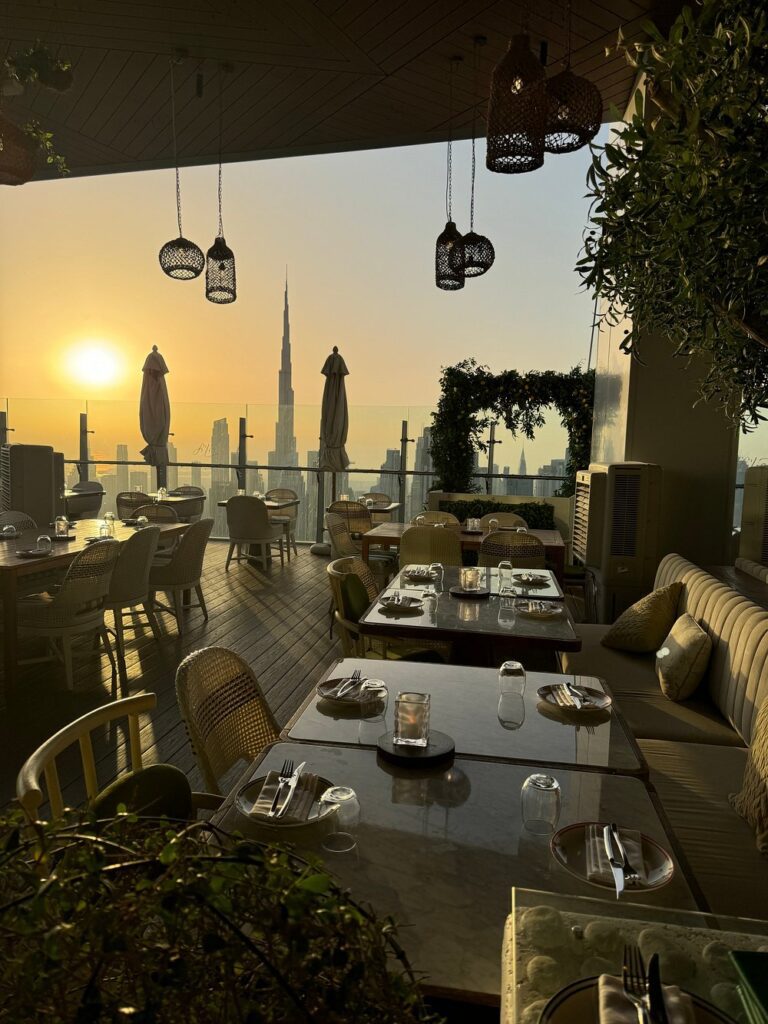 Fi’lia rooftop restaurant at sunset with Burj Khalifa view and candlelit tables.
